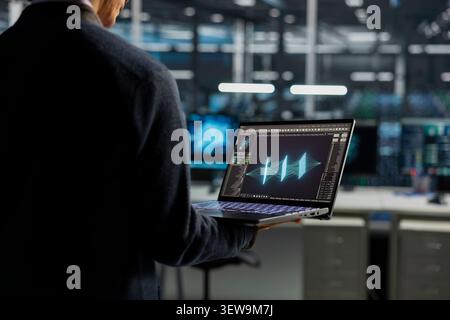 Data center technician uses a desktop computer in a data center to manage AI systems and optimize server infrastructure. Stock Photo