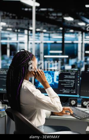 IT expert provides technical support from a data center using a headset while troubleshooting client server issues. Stock Photo