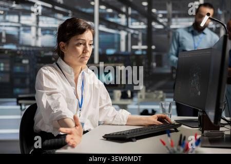 IT specialist uses a digital device in a data center to run hardware diagnostics and maintain operational stability. Stock Photo