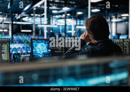 Data center programmer uses a digital device in a data center to manage AI systems and optimize server infrastructure. Stock Photo