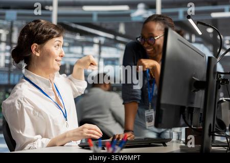 Cheerful data center team shares a fist bump in a data center after improved performance and completed server operations. Stock Photo