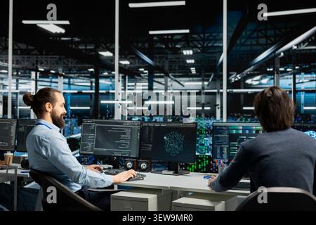 Data center programmers use a desktop computer in a data center to manage AI systems and optimize server infrastructure. Stock Photo