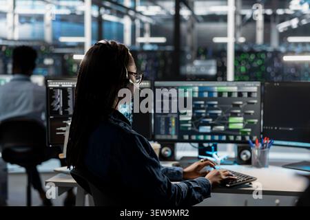 IT expert provides technical support from a data center using a headset while troubleshooting client server issues. Stock Photo