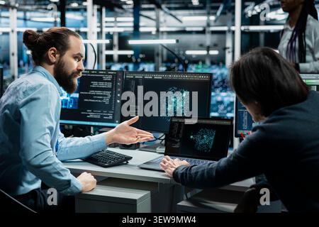 Server room colleagues use a digital device in a data center to manage AI systems and optimize server infrastructure. Stock Photo