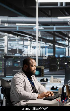 System administrator reviews performance analytics on a desktop computer in a data center to optimize storage systems and resource use. Stock Photo