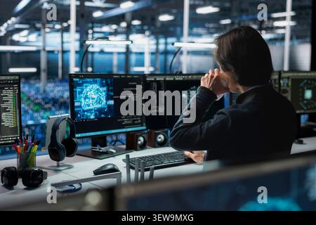 Data center technician uses a digital device in a data center to support automation monitoring and reliable server workflows. Stock Photo
