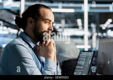 Computer scientist uses a desktop computer in a data center to manage AI systems and optimize server infrastructure. Stock Photo