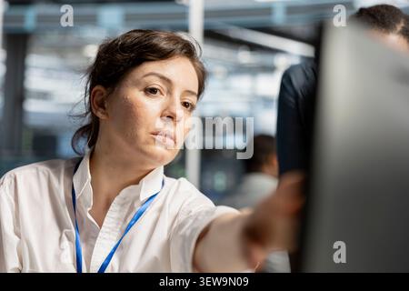 Data center engineer uses a digital device in a data center to run hardware diagnostics and maintain operational stability. Stock Photo