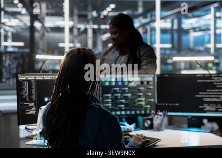 System administrator uses a desktop computer in a data center to manage AI visualization and optimize server infrastructure. Stock Photo
