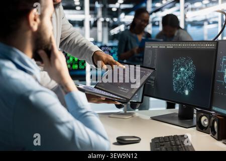 Concerned data center team reviews warning messages in a data center while troubleshooting errors affecting equipment performance. Stock Photo