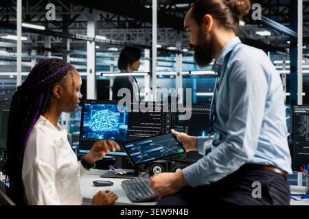 Software developer reviews artificial intelligence systems and machine learning processes inside a data center. Stock Photo