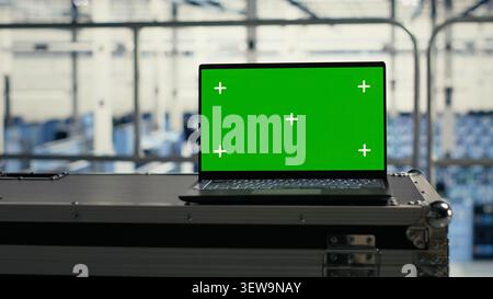 Technology specialist uses a green screen laptop in a server room for AI workflow and screen replacement. Stock Photo