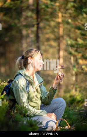 Smiling woman mushroomer forager found fresh edible boletus mushrooms in autumn pine forest. Stock Photo