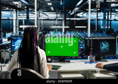 Data center technician uses a chroma key computer to review server hardware stability and infrastructure maintenance. Stock Photo
