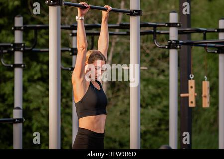 Fit woman hanging from bar at an outdoor gym Stock Photo
