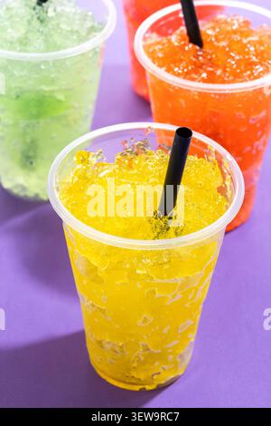 Colorful Frozen Slush Drinks in Plastic Cups on violet background Stock Photo