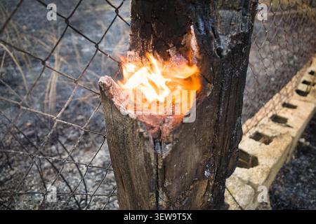 Smoldering wooden fence post burning after a fire Stock Photo