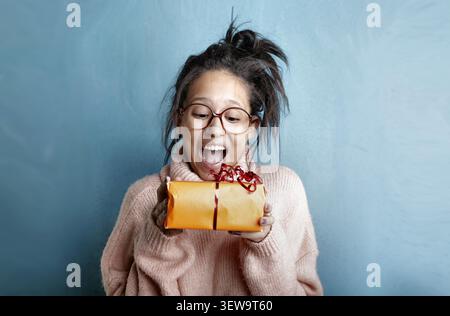 Surprised young woman with glasses holding a gift Stock Photo