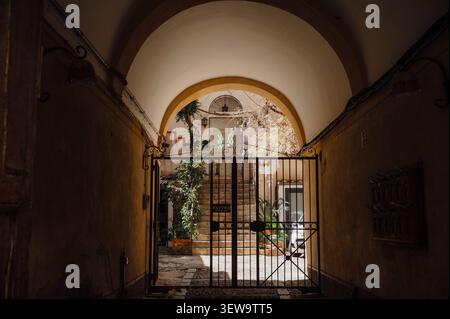 Arched entrance leading to a quiet courtyard in Cefalù, Sicily Stock Photo