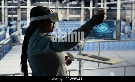 Data center engineer uses a VR headset to review AI diagnostics and manage server system performance. Stock Photo