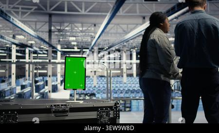 System administrator uses a green screen tablet in a server room for AI workflow and screen replacement. Stock Photo