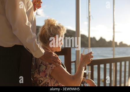 Senior couple enjoying wine on a deck at sunset Stock Photo