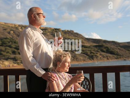 Senior couple enjoying wine on a scenic balcony Stock Photo