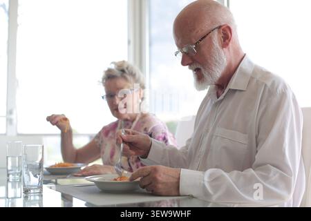 Senior couple eating lunch together at home Stock Photo