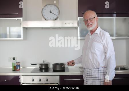 Happy senior man cooking in his modern kitchen Stock Photo