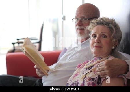 Elderly couple relaxing together on a sofa Stock Photo