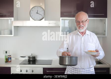 Happy senior man serving pasta for dinner at home Stock Photo