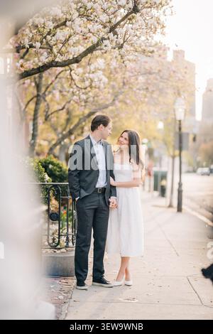 Couple holding hands on a city sidewalk in spring Stock Photo