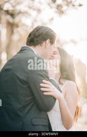 Romantic couple kissing on wedding day at sunset Stock Photo