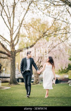 Smiling couple walks hand in hand through a park Stock Photo