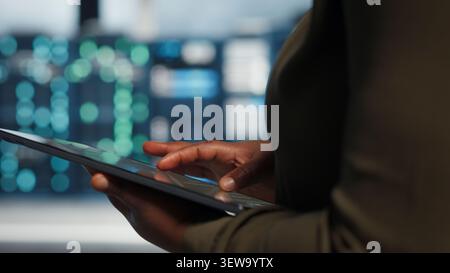 Programmer uses tablet in a server farm to plan disaster recovery and strengthen data protection. Stock Photo