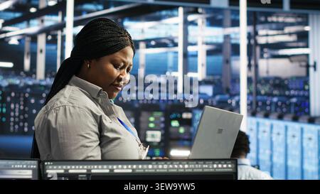Data center administrator uses laptop node tree software to review analytics and identify equipment issues. Stock Photo