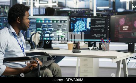 Engineer using a wheelchair reacts to a slow AI node tree tool while working in a data center. Stock Photo
