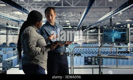 Data center colleagues use laptop deep learning tools in a server room to improve AI operations and system efficiency. Stock Photo