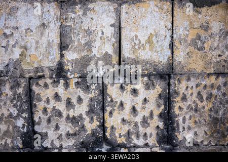 Weathered concrete blocks with peeling paint and dark stains. Textured surface shows signs of aging and exposure Stock Photo