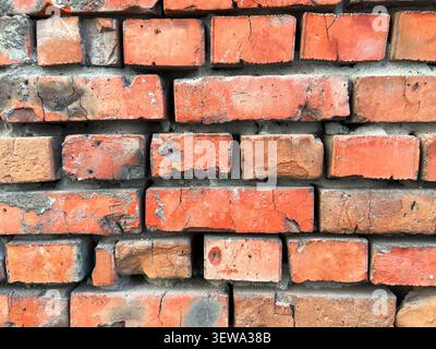 Weathered red brick wall with aged mortar joints showing cracks and wear in a close-up view Stock Photo
