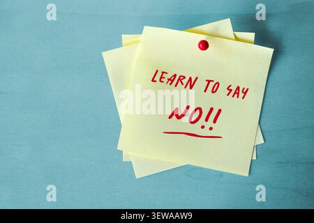 Yellow sticky notes with text Learn to say No, attached with a red pin on a blue background, concept for confidence and preventing exploitation, copy Stock Photo