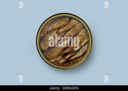 Still life view from above of sprats in oil in round can on blue background Stock Photo