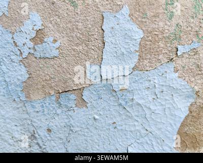 Grunge abstract background showing old weathered wall with peeling light blue paint and exposed rough plaster. Copy space Stock Photo