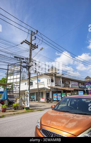 A dynamic vertical lifestyle photograph captured from a moving vehicle, showcasing a colorful street in a Thai coastal town Stock Photo