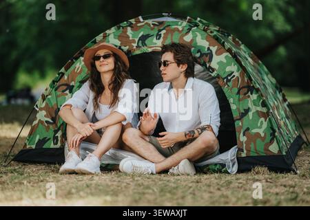 Young couple relaxing in a camouflage tent during a casual outdoor summer camping trip Stock Photo
