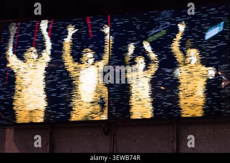 Fans rendered as digital silhouettes celebrate on a screen at Wembley Stadium, London Stock Photo