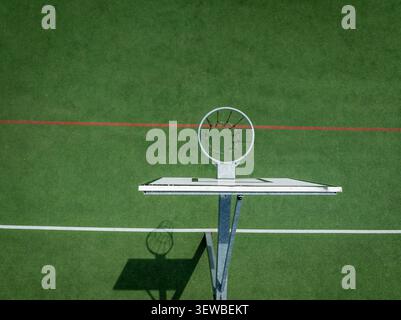 Aerial view of a basketball hoop on a green court with white and red lines in Warmian-Masurian Voiv, Poland. Stock Photo
