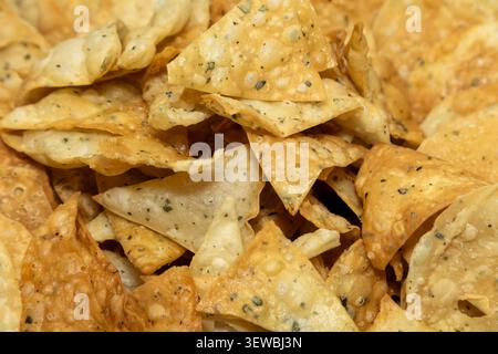 A close-up view of a pile of golden-brown, irregularly shaped tortilla chips, perfect for dipping or enjoying on their own Stock Photo