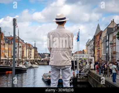 Man in a hat watches the harbor on a partly cloudy summer day in Copenhagen, Denmark Stock Photo