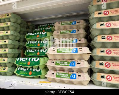 Khimki, Russia - June 25, 2026: Egg cartons stacked on supermarket shelf, featuring various brands and labels in green and beige colors Stock Photo
